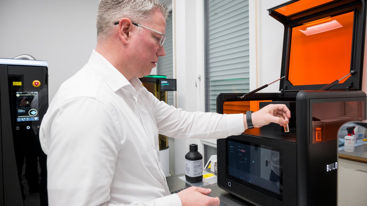 Christian Steinhage, Geschäftsführer der Naddcon GmbH, steht an einem 3D-Drucker, der in flüssigem Harz Objekte drucken kann.