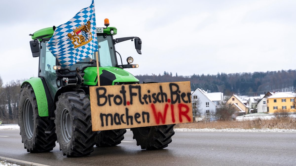 Ein Traktor bei Zusmarshausen mit Bayernfahne und einem Schild mit der Aufschrift "Brot.Fleisch.Bier machen WIR". 