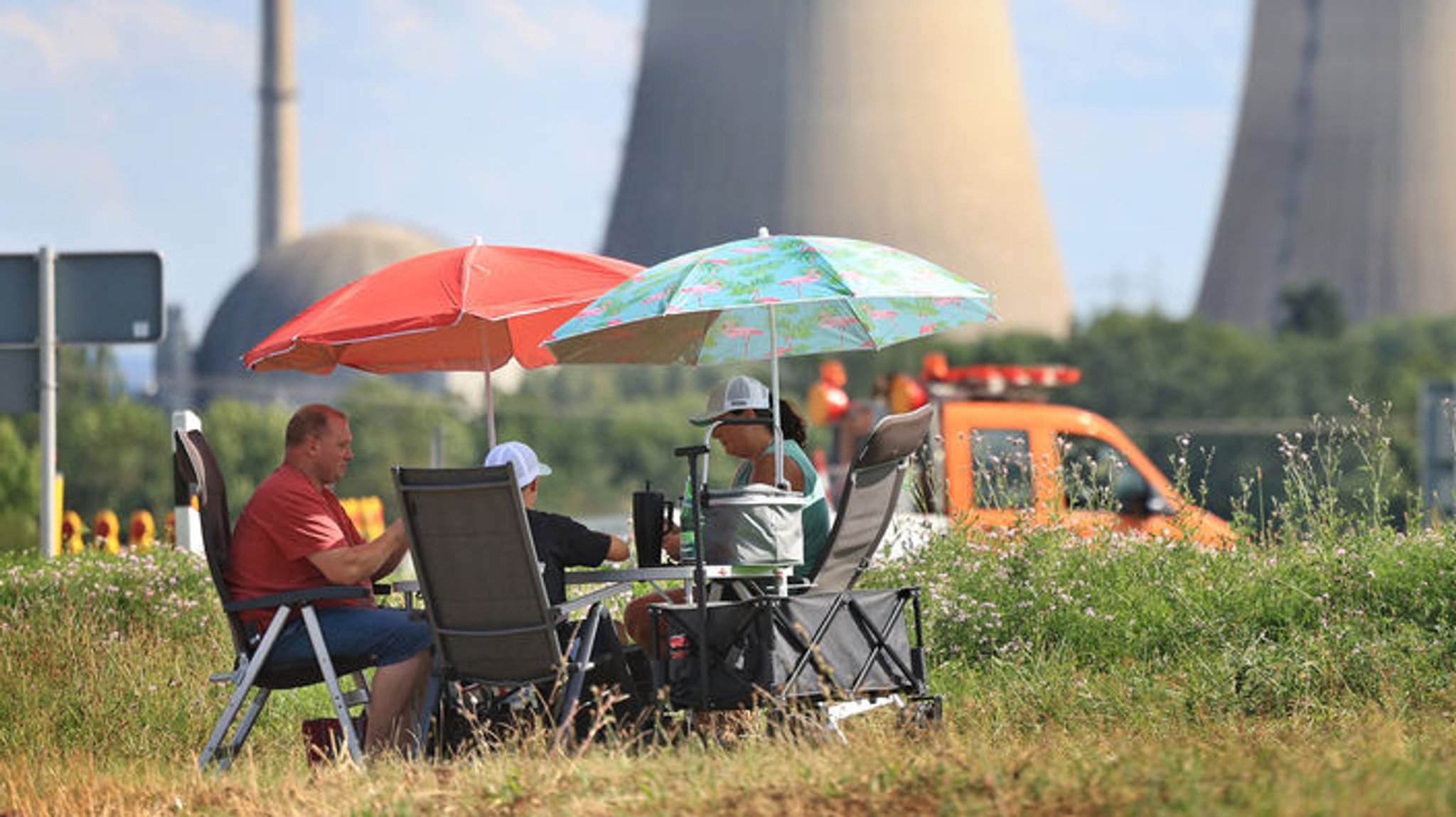 16.08.2024, Bayern, Grafenrheinfeld: Schaulustige warten in Liegestühlen unter Sonnenschirmen auf die Sprengung der Kühltürme des stillgelegten Kernkraftwerkes. Das Kernkraftwerk Grafenrheinfeld war von 1982 bis 2015 in Betrieb. Die Anlage durfte nach der Atomkatastrophe im japanischen Fukushima im Jahr 2011 zwar wieder hochfahren, am 27. Juni 2015 war dann aber endgültig Schluss. Seit 2018 wird das Kraftwerk zurückgebaut. Foto: Karl-Josef Hildenbrand/dpa +++ dpa-Bildfunk +++