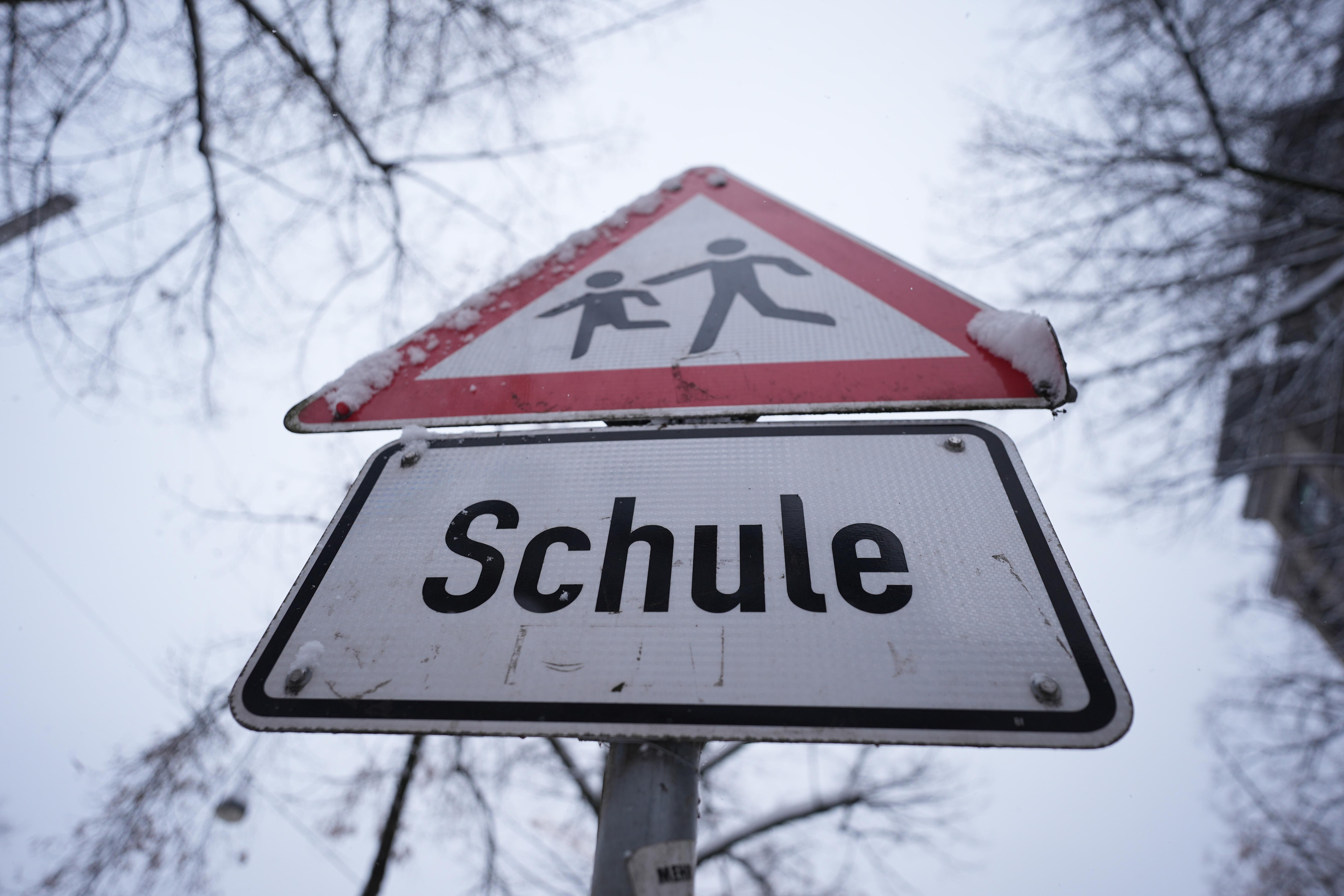 Verschneites Verkehrsschild vor einer Schule
