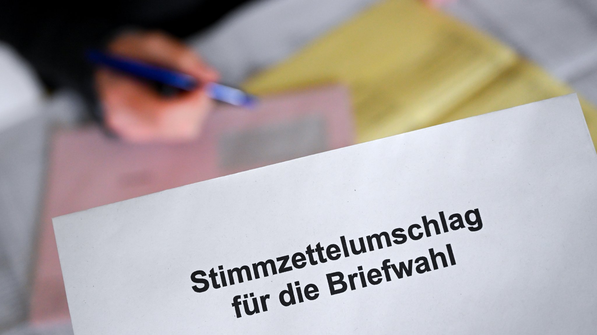 Eine Frau beschäftigt sich mit den Briefwahlunterlagen für die Kommunalwahl 2026 in Bayern. 
