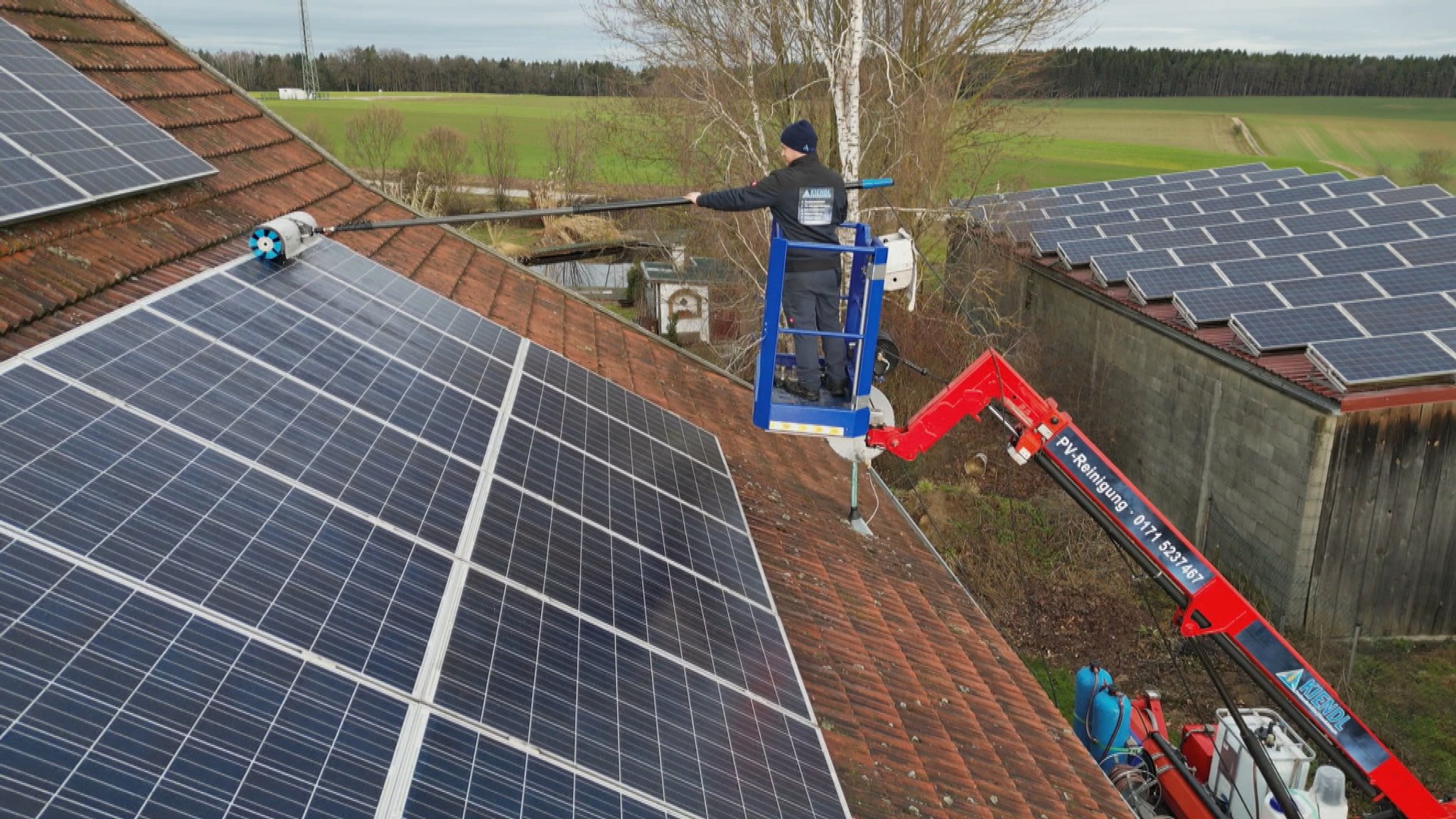 Ein Mann beim Reinigen der Paneele einer großen Photovoltaik-Anlage