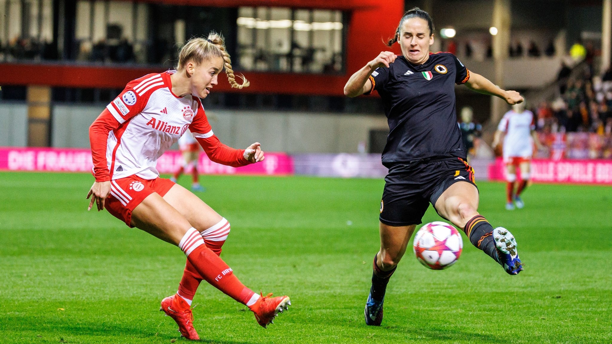 Giulia Gwinn vom FC Bayern München (l) und Evelyne Viens vom AS Rom im Zweikampf um den Ball. 