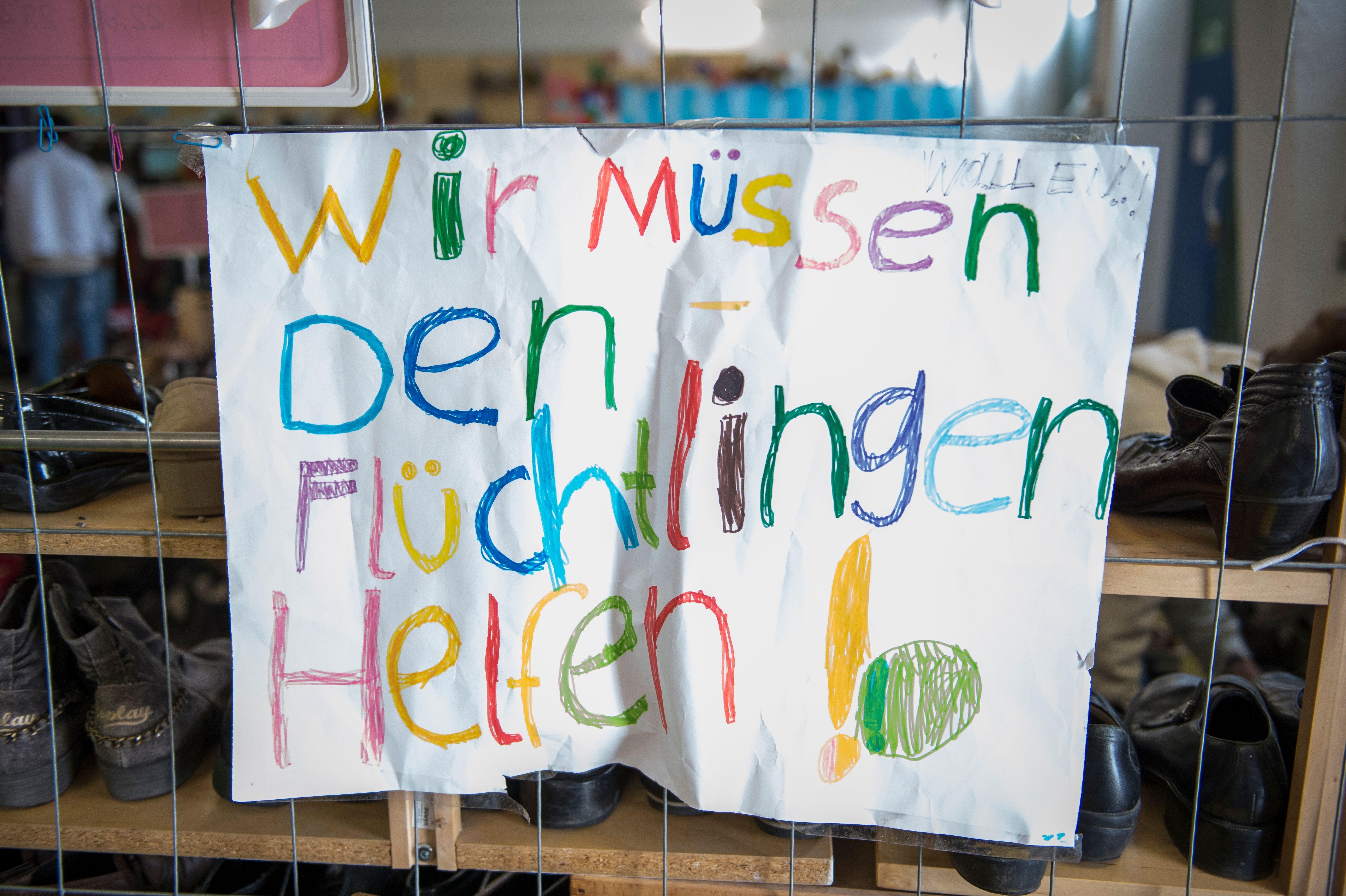 Ein buntes Plakat mit der Aufschrift: "Wir müssen den Flüchtlingen helfen!"