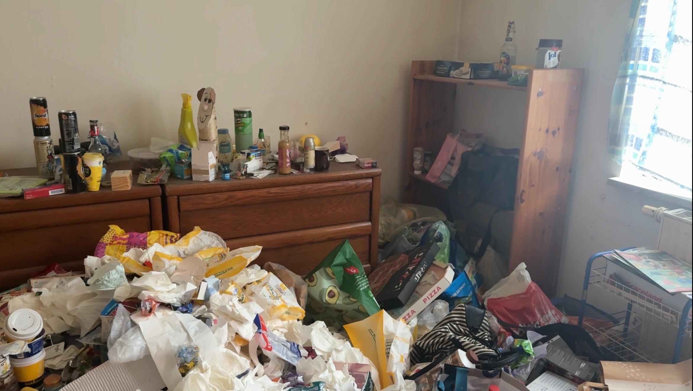 Verwahrlostes Zimmer mit Müll, der sich stapelt.