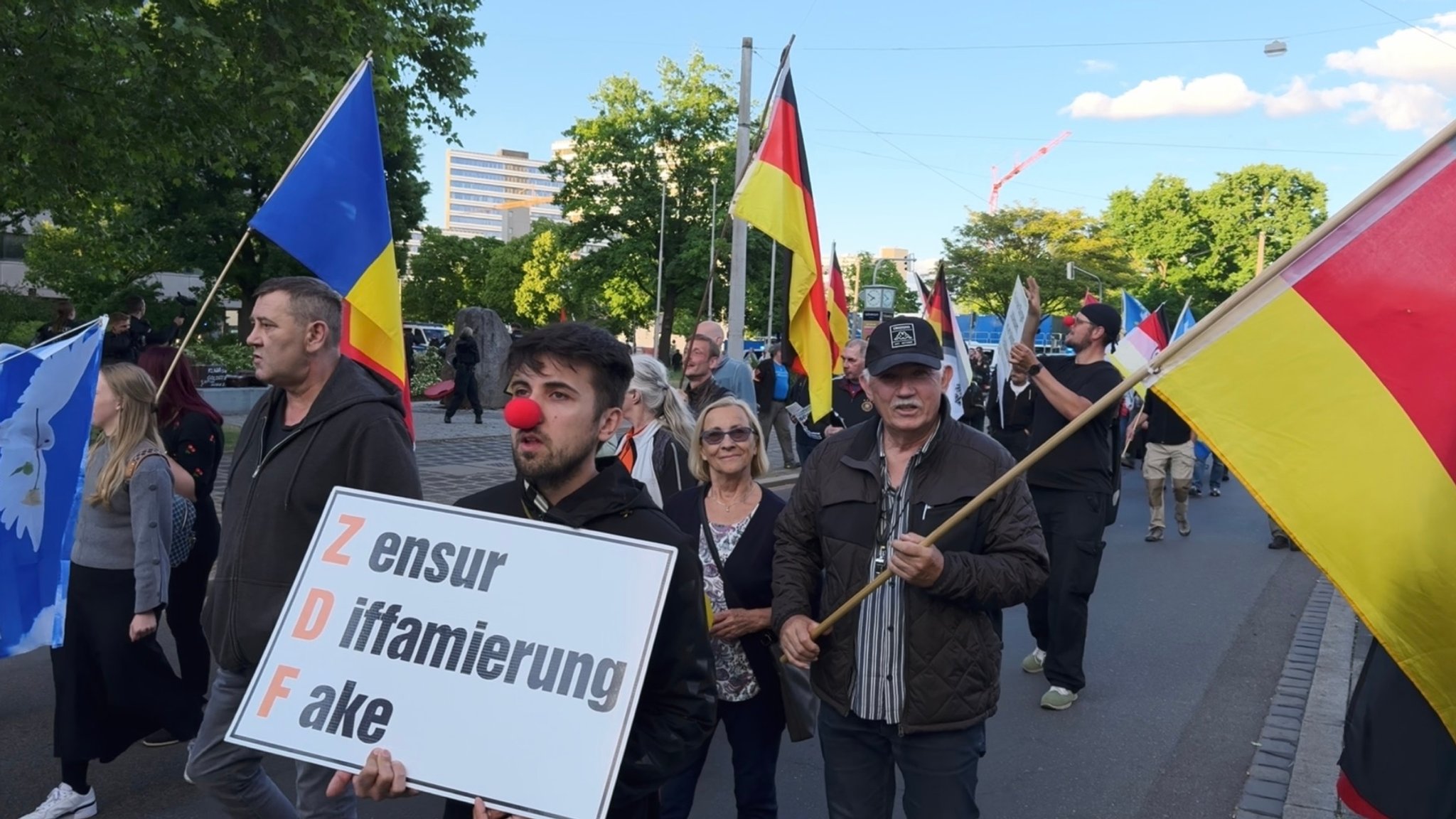 Ein Mann trägt ein Schild, auf dem "Zensur, Diffamierung, Fake" steht. 