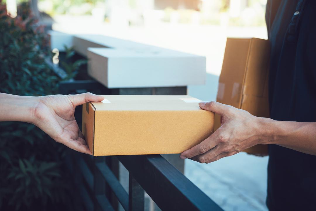 Ein Kurier übergibt ein Paket an Kundschaft.