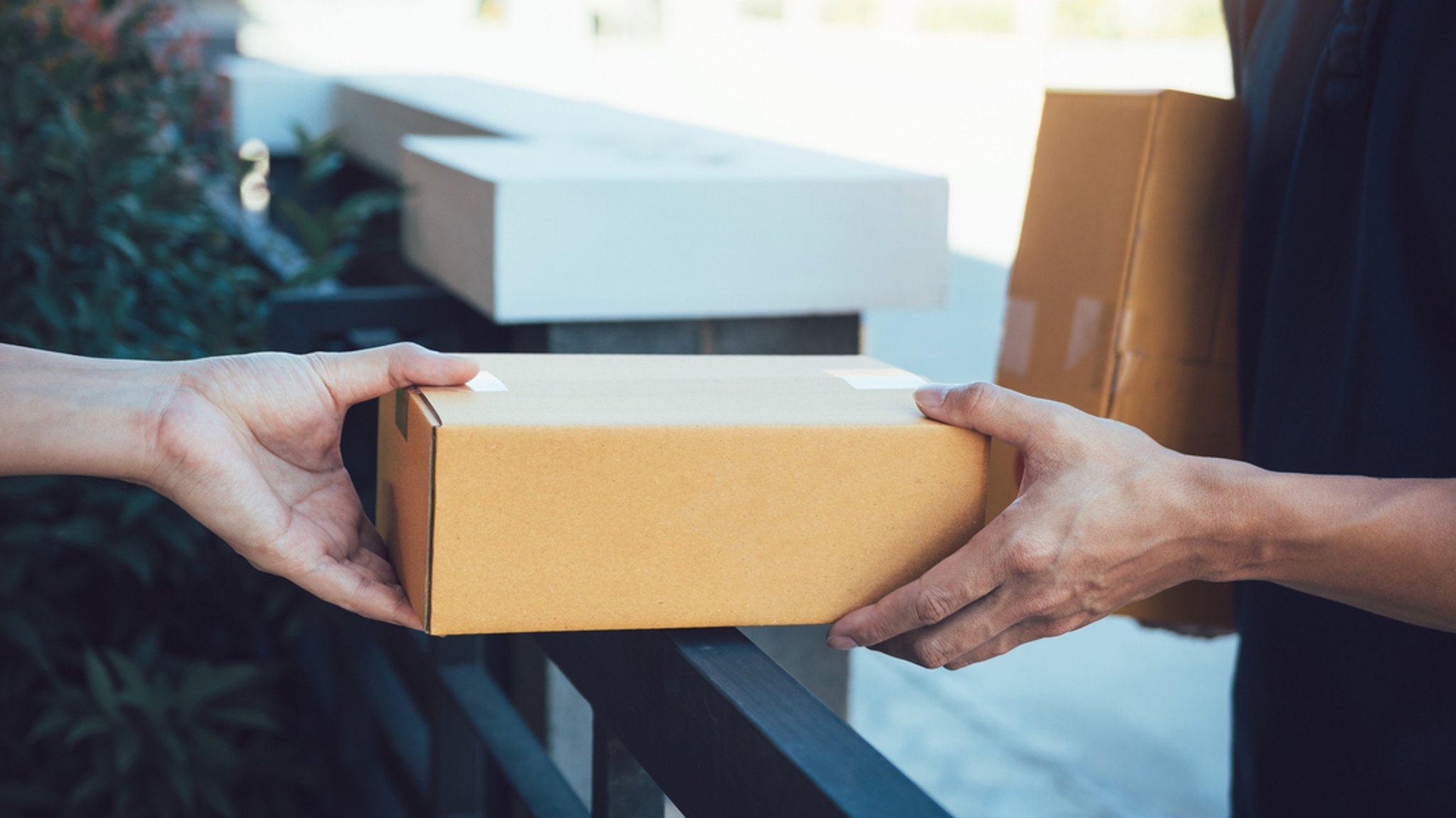 Ein Kurier übergibt ein Paket an Kundschaft.