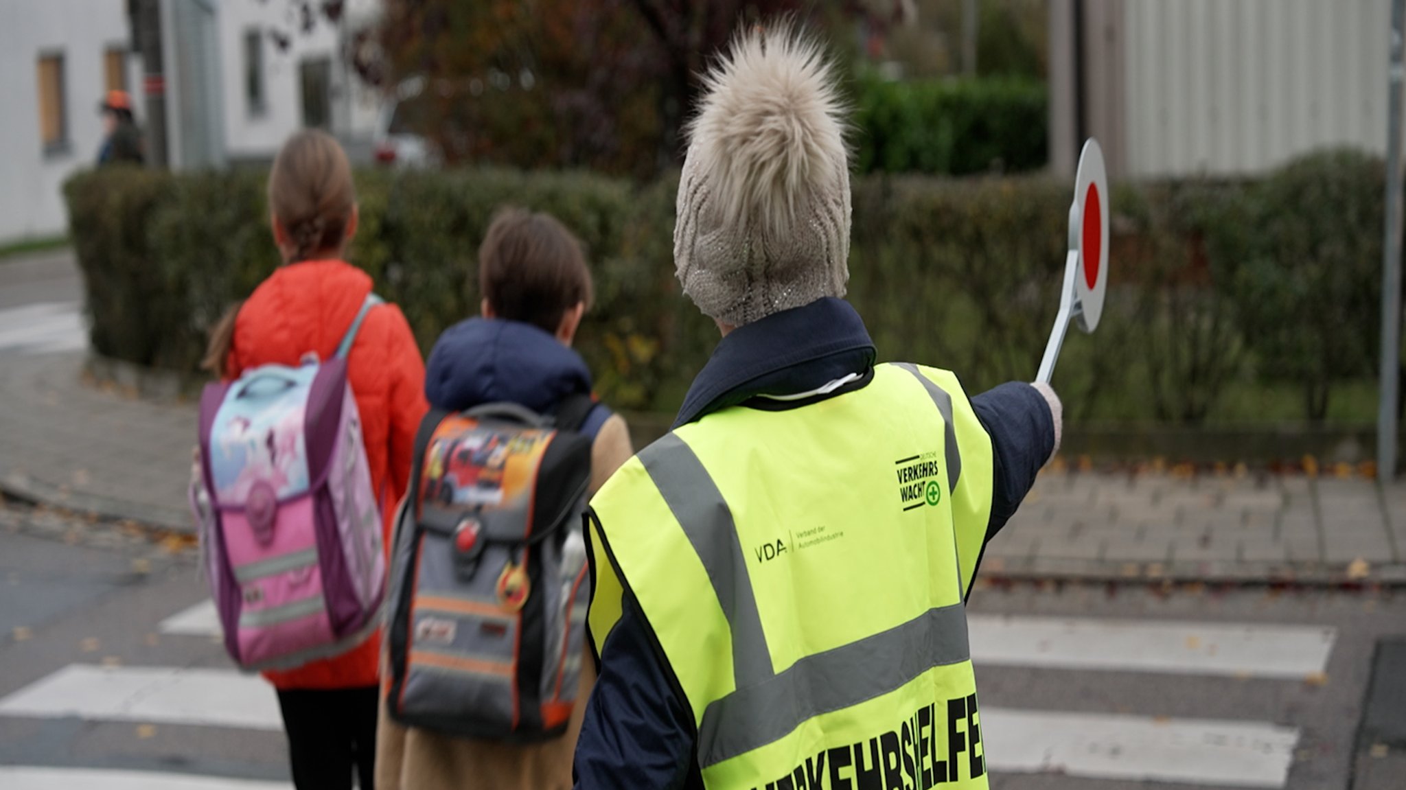 Eine Schülerlotsin hilft Schülern über die Straße. 