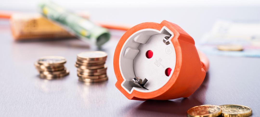 Steckdose mit Münzen und Geldscheinen.