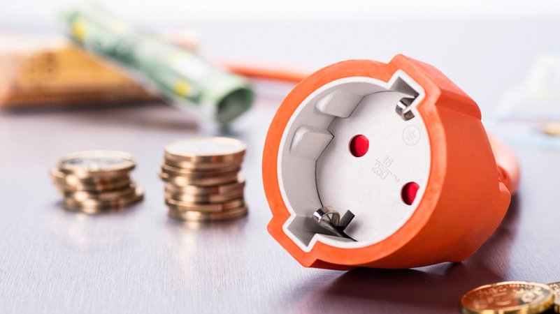 Steckdose mit Münzen und Geldscheinen. | Bild: stock.adobe.com/gopixa Steckdose mit Münzen und Geldscheinen.