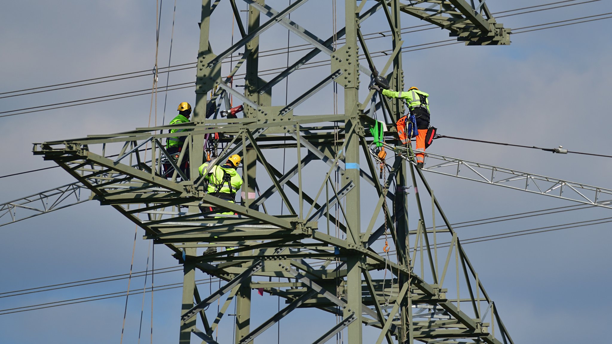 Arbeiter auf einem Strommasten beim Ausbau einer Stromtrasse