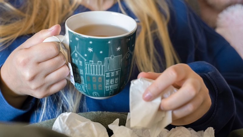(Symbolbild) Eine Frau trinkt Tee und hält ein Taschentuch in ihrer Hand. | Bild: picture alliance/dpa | Alicia Windzio (Symbolbild) Eine Frau trinkt Tee und hält ein Taschentuch in ihrer Hand.