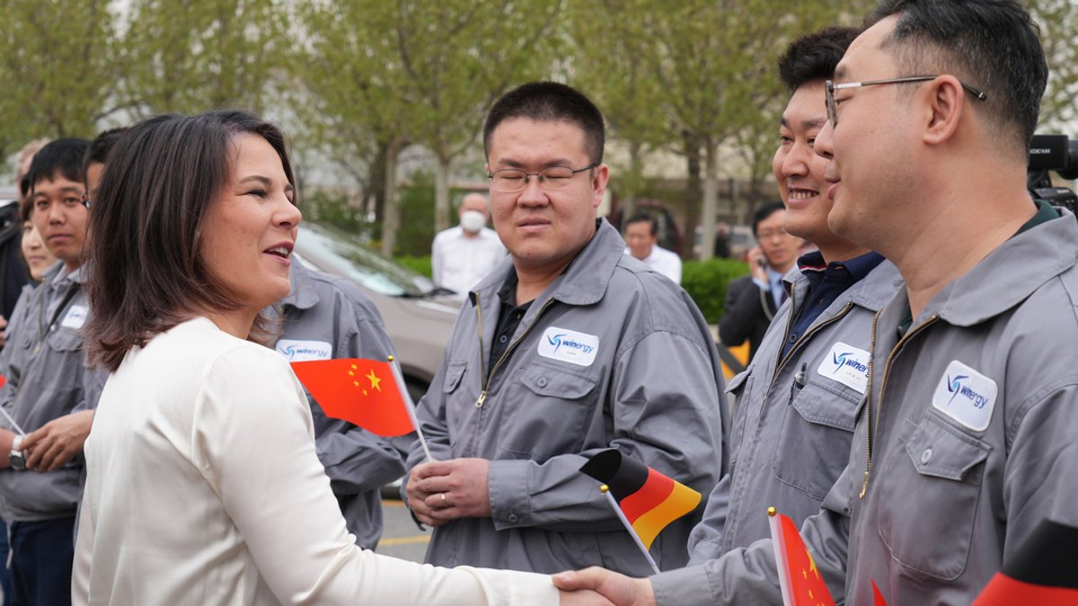 Außenministerin Annalena Baerbock (Grüne) besichtigt die Flender GmbH und wird von Arbeitern mit deutschen und chinesischen Papierfähnchen begrüßt.