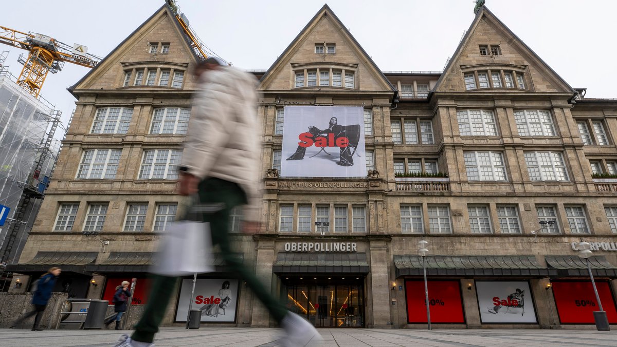 Passanten laufen vor Geschäftsöffnung an einem Eingang zum Luxus-Kaufhaus Oberpollinger in der Münchner Innenstadt vorbei.