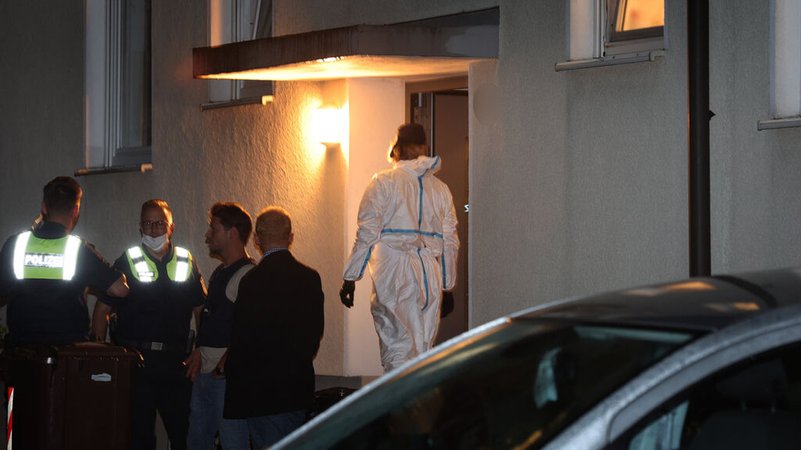 28.07.2023, Bayern, Langweid: Polizisten und ein Beamter der Spurensicherung stehen vor einem Haus, in dem drei Menschen erschossen wurden. 