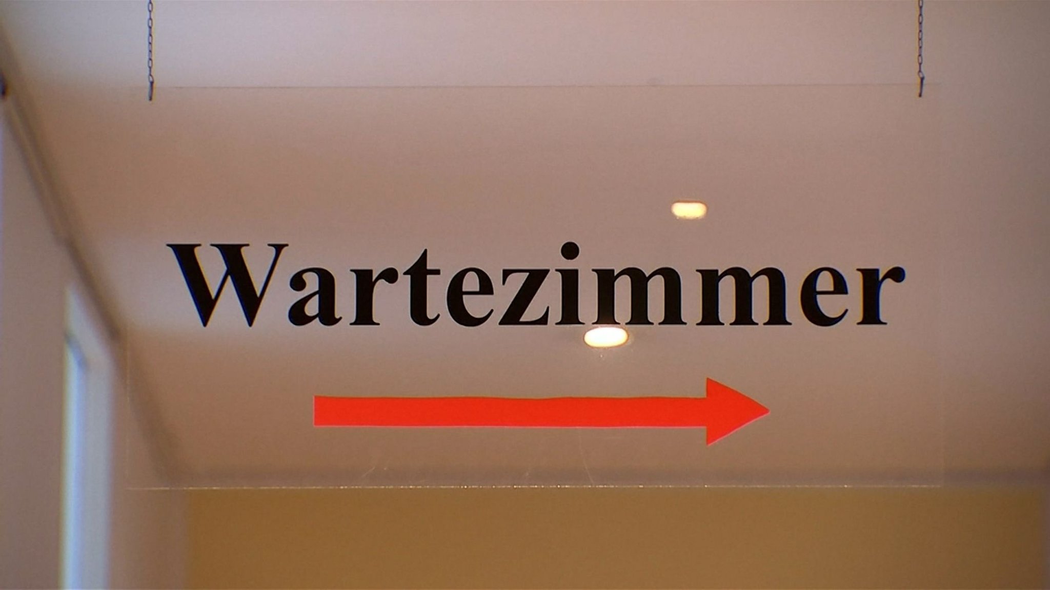 Ein Hinweisschild weist den Weg ins Wartezimmer einer Arztpraxis.