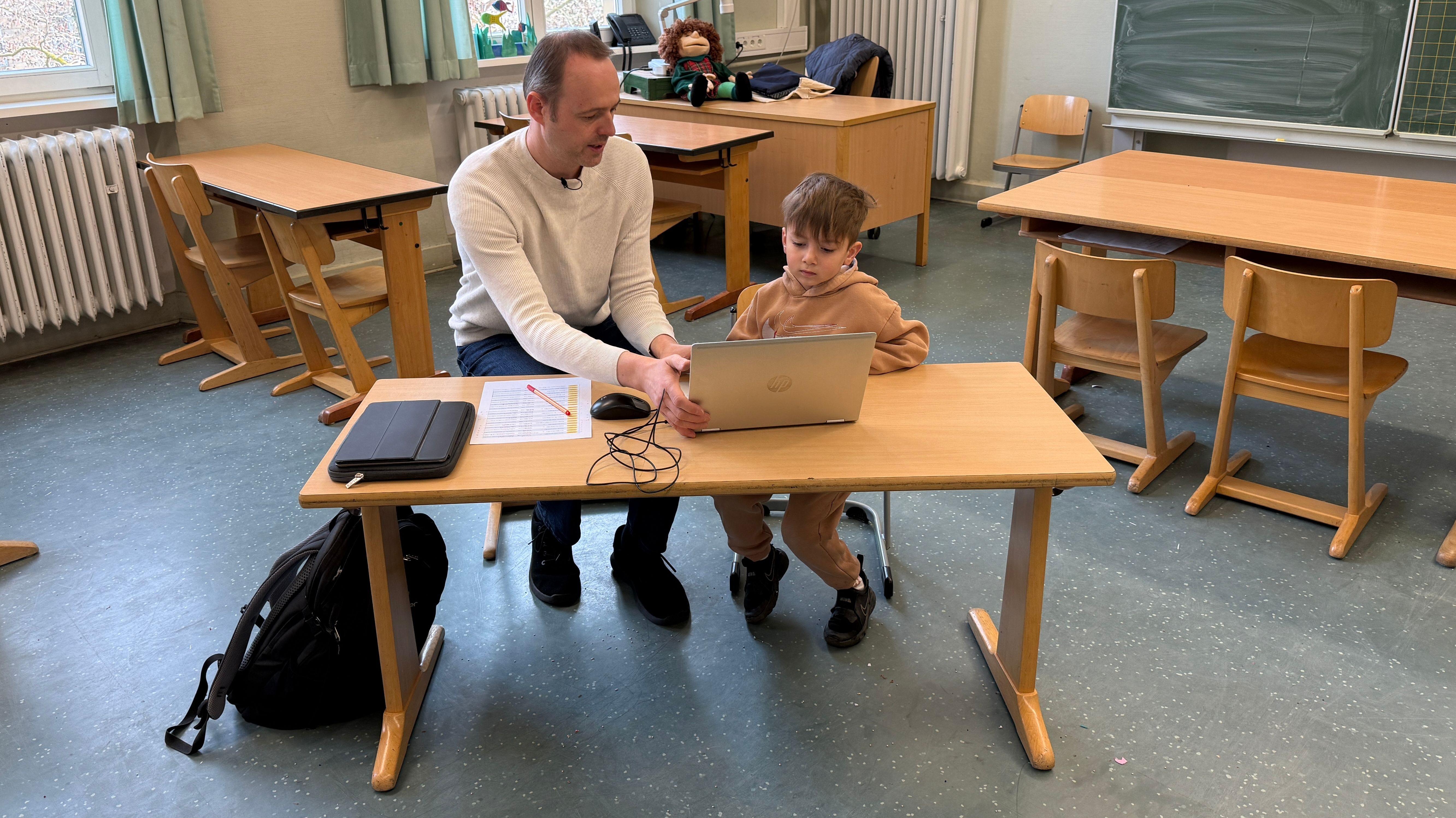 Beratungslehrer Matthias Helbig macht Sprachstandstest mit vierjährigem Poyraz in einem Klassenzimmer. Die beiden sitzen dazu an einem Laptop. 