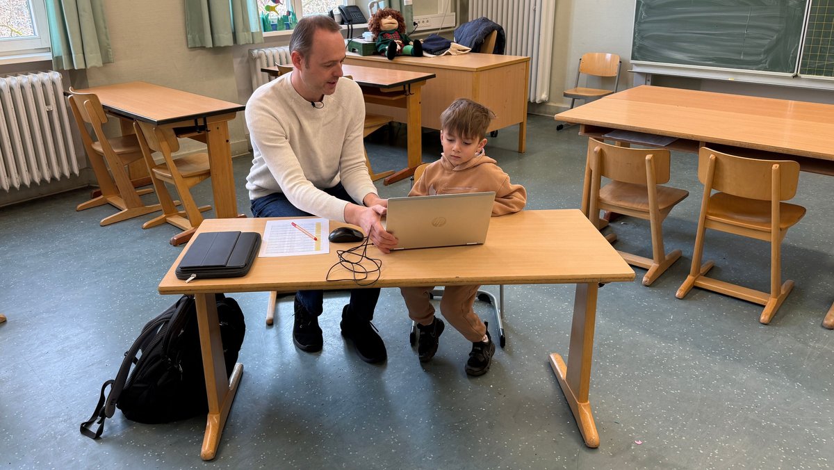 Beratungslehrer Matthias Helbig macht Sprachstandstest mit vierjährigem Poyraz in einem Klassenzimmer. Die beiden sitzen dazu an einem Laptop. 