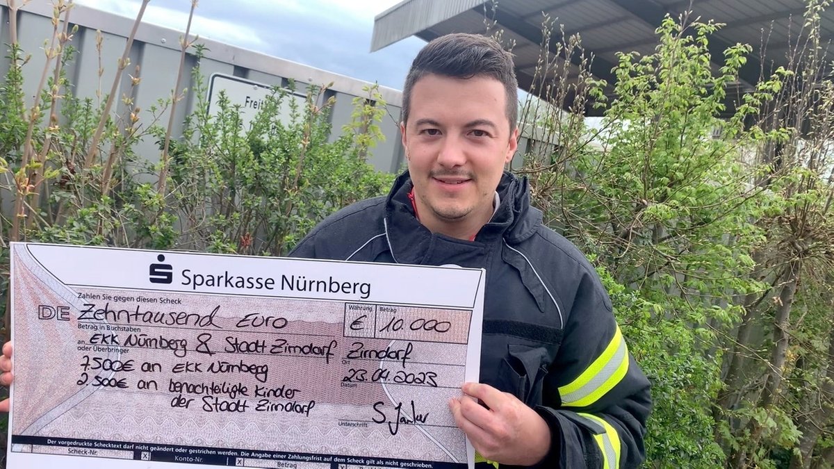 Stefan Janker, ChaRUNity-Veranstalter und Berufsfeuerwehrmann zeigt den Scheck mit den Spendengeldern.