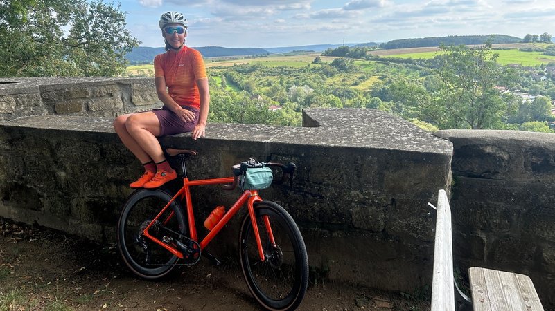 Pause mit dem Gravelbike mit Ausblick auf die Burg von Königsberg in den Haßbergen. | Bild: BR / Achim Winkelmann Pause mit dem Gravelbike mit Ausblick auf die Burg von Königsberg in den Haßbergen.