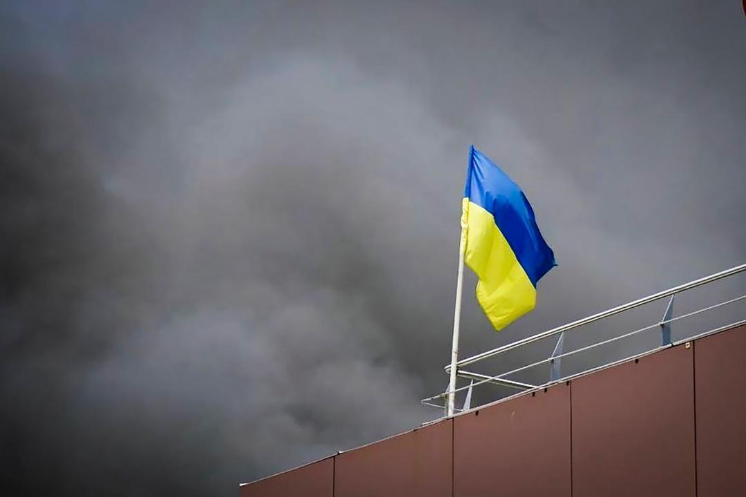Eine ukrainische Flagge vor schwarzem Rauch.