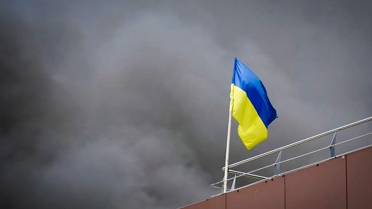 Eine ukrainische Flagge vor schwarzem Rauch.