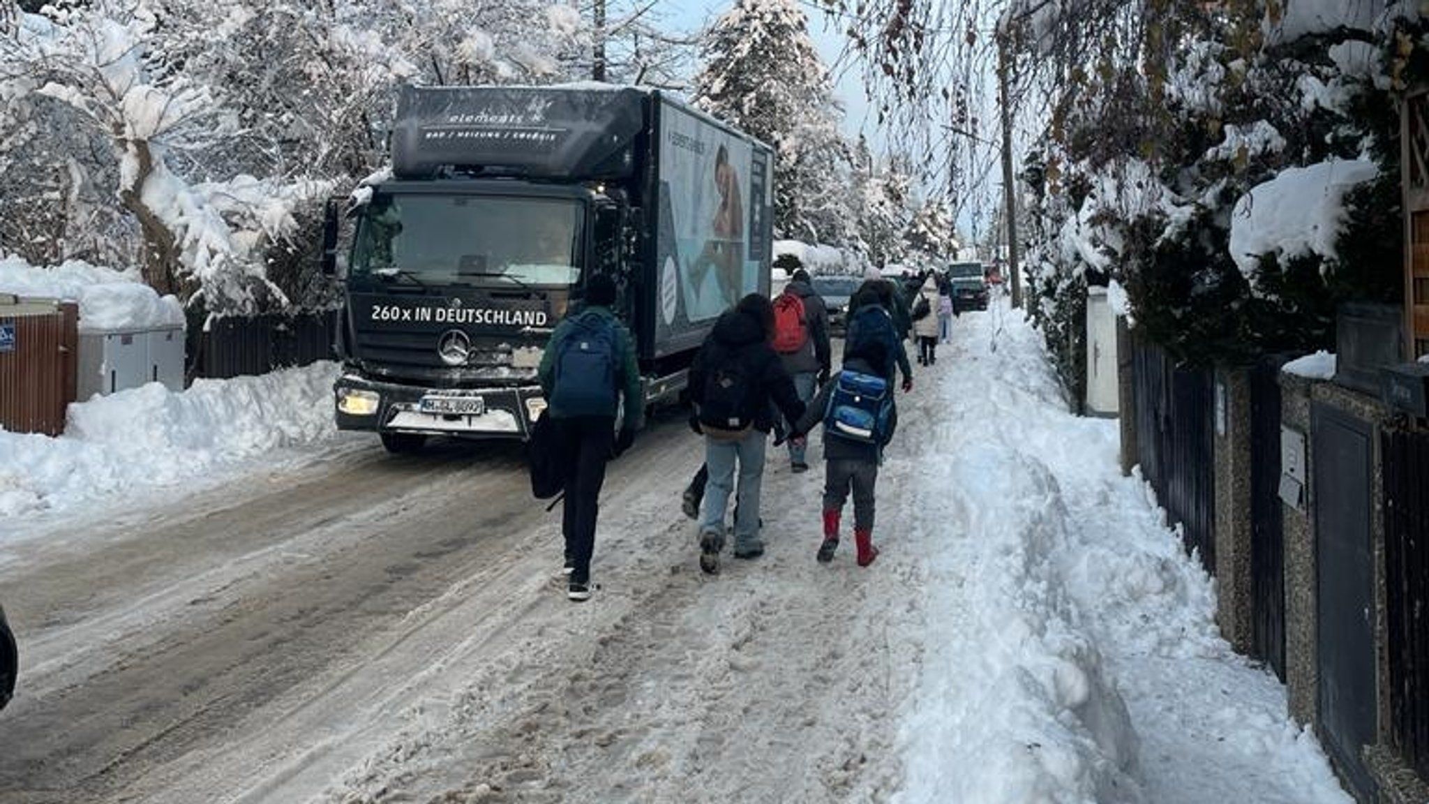 Eine vereiste Straße in München - Menschen gehen zu Fuß auf der einen Seite, Autos auf der anderen Seite