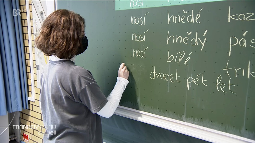 Eine Lehrerin schreibt tschechische Worte an die Tafel 