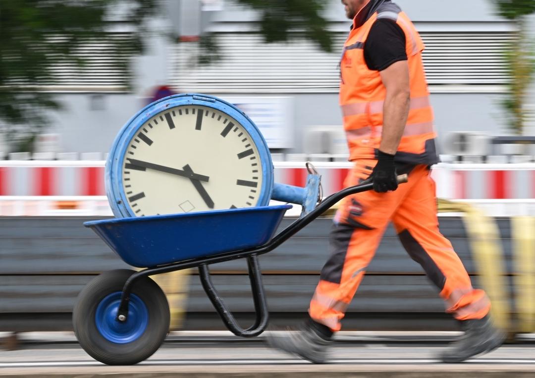 Symbolbild: Ein Arbeiter transportiert eine Bahnhofsuhr auf einer Schubkarre. 