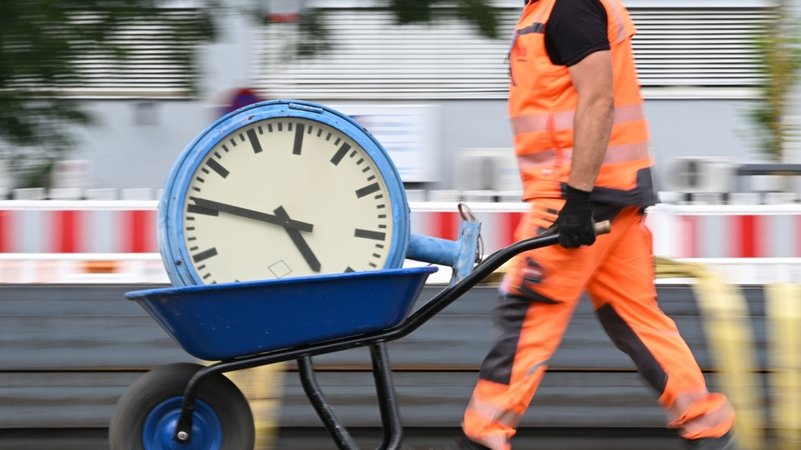 Symbolbild: Ein Arbeiter transportiert eine Bahnhofsuhr auf einer Schubkarre. | Bild: dpa-Bildfunk/Arne Dedert Symbolbild: Ein Arbeiter transportiert eine Bahnhofsuhr auf einer Schubkarre.