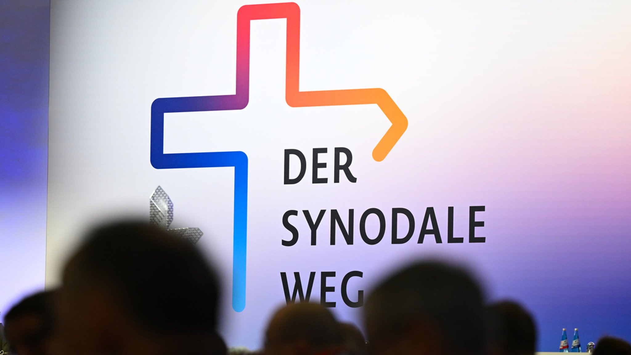 Teilnehmer der Synodalversammlung sitzen vor dem Schriftzug "Der Synodale Weg". 