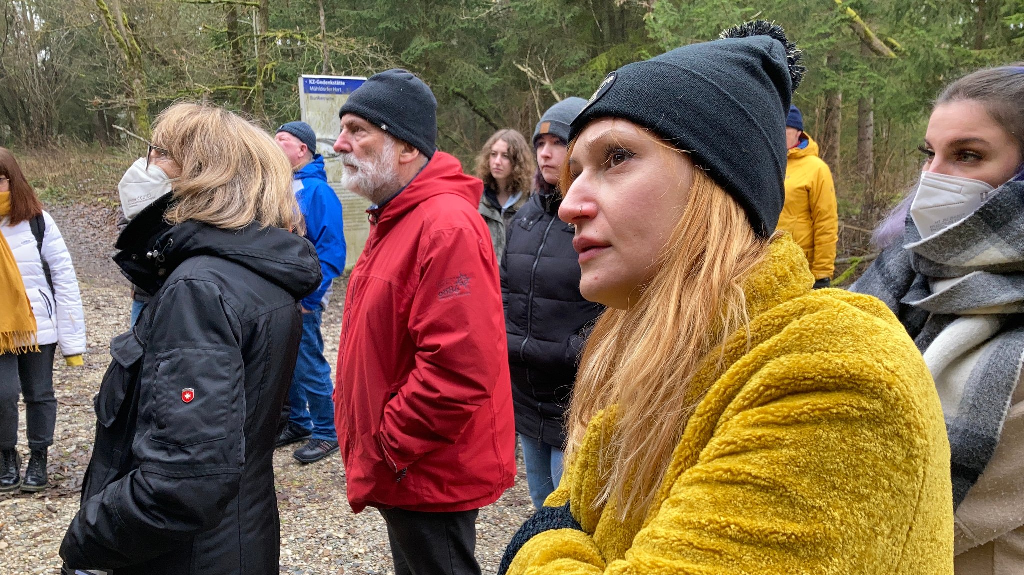 Eine Gruppe von Menschen, die das Jugendbüro Burghausen eingeladen hat, schauen sich den massiven Betonbogen im Waldgebiet Mühldorfer Hart an.