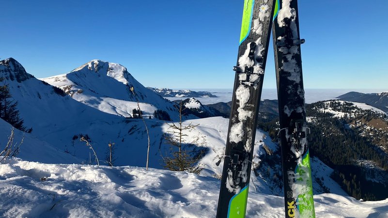 Zwei Tourenski stecken im Schnee, dahinter ragen schneebedeckte Gipfel in den blauen Himmel. | Bild: BR / Ulrike Nikola Zwei Tourenski stecken im Schnee, dahinter ragen schneebedeckte Gipfel in den blauen Himmel.