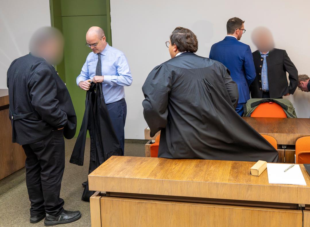 28.10.2025: Die zwei beschuldigten Bahnmitarbeiter (links und rechts) stehen vor Prozessbeginn um das tödliches Zugunglück in Garmisch-Partenkirchen vom 3. Juni 2022 mit ihren Anwälten zusammen im Gerichtssaal des Landgericht München II. 