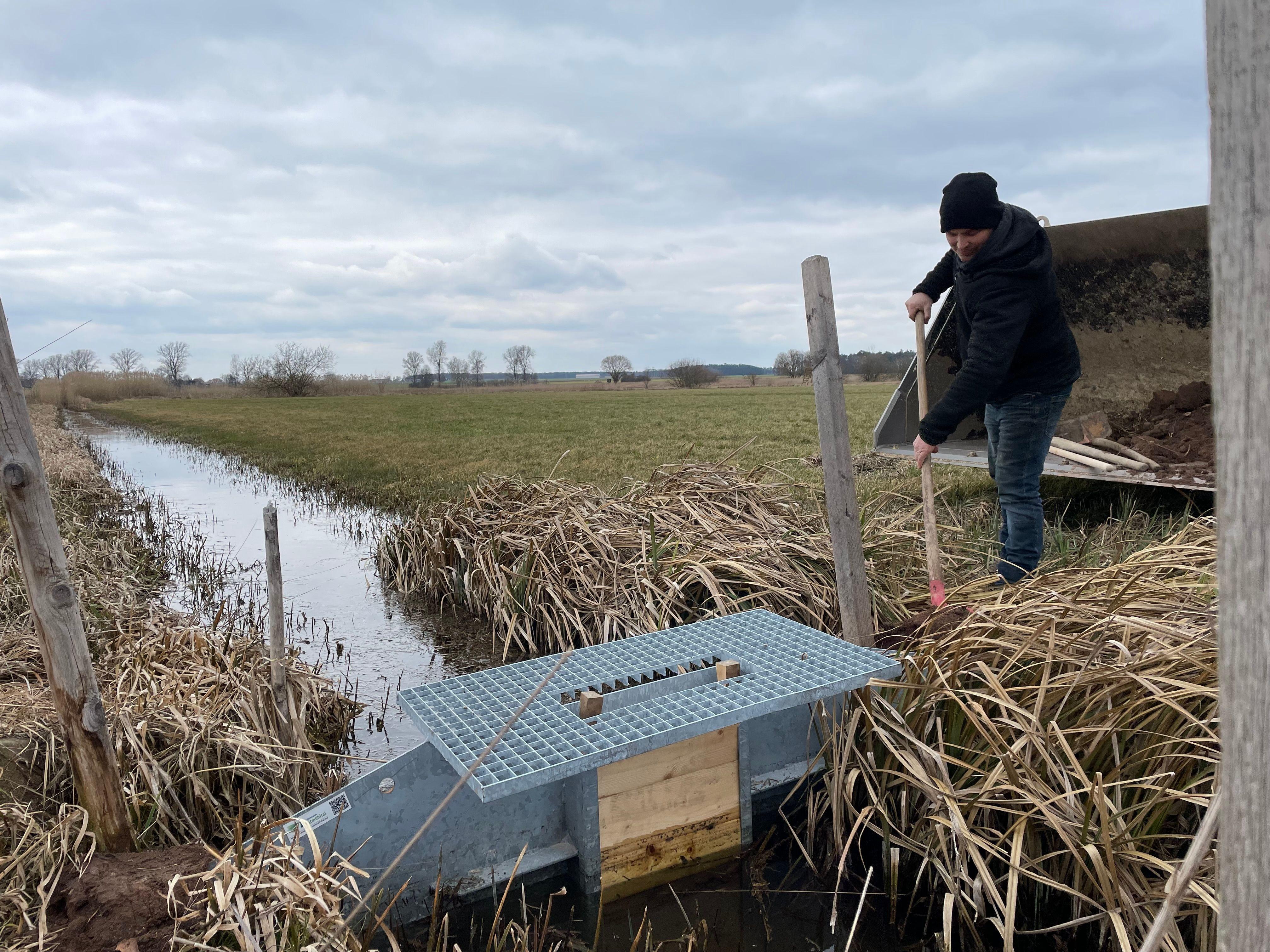 Ein Mann mit Schaufel an einem aufgestauten Graben im Oberen Altmühltal bei Gunzenhausen.