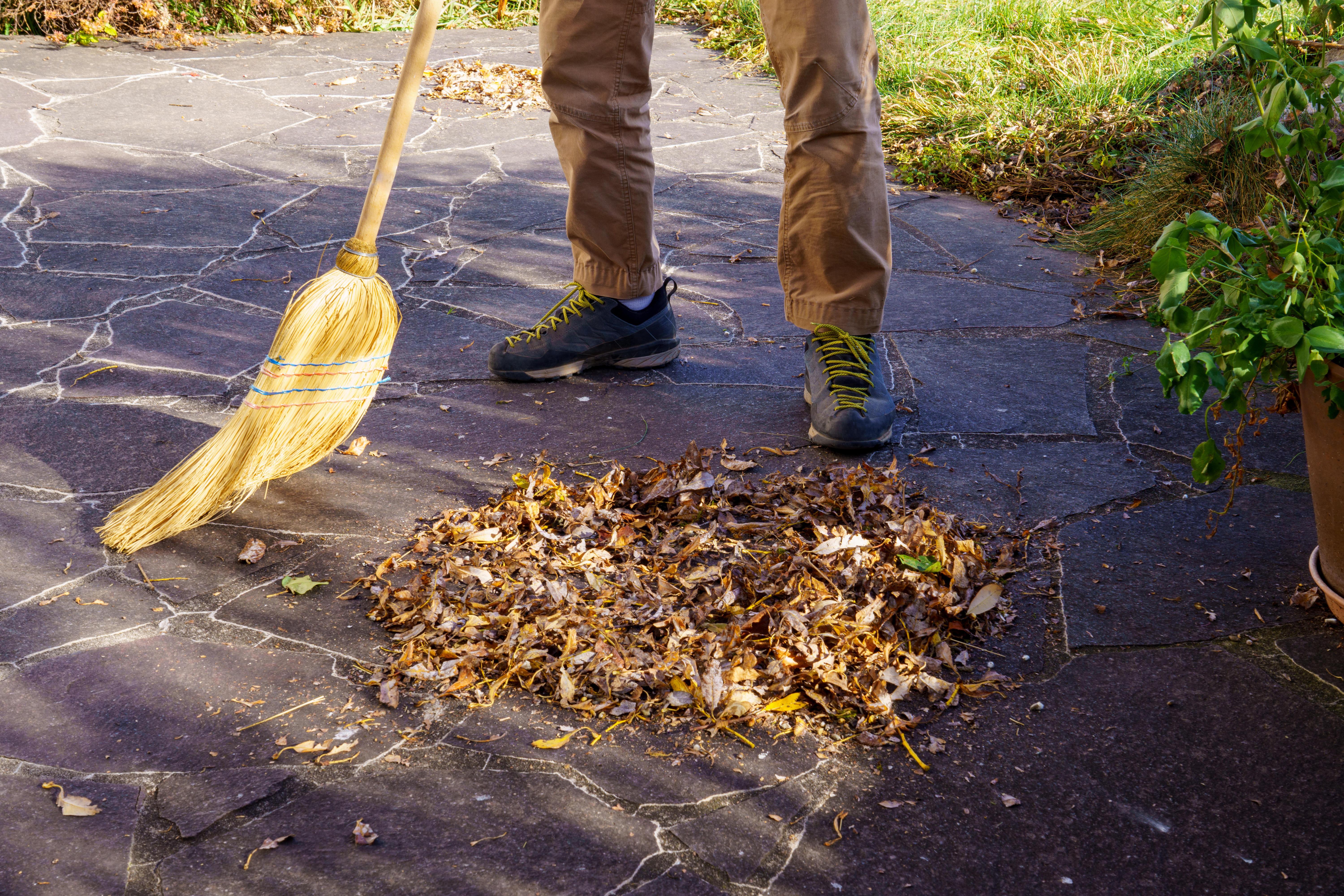 ARCHIV (09.11.2024) Gartenarbeit: Laub auf der Terrasse mit Strohbesen zusammenkehren und Laubhaufen bilden)
