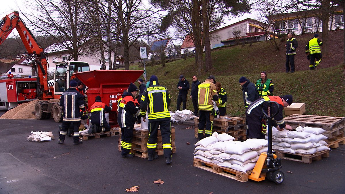 Feuerwehrleute befüllen Sandsäcke in Gräfendorf.