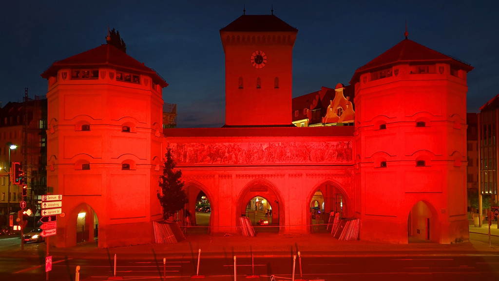 Das Isartor in München bei Dunkelheit - rot angestrahlt, mit einer Installation des Lichtkünstlers und Fotografen Markus Julian Mayer. In der Anlage gibt es jeden Abend Vorträge und Kulturveranstaltungen zu wichtigen Fragen der Architektur.