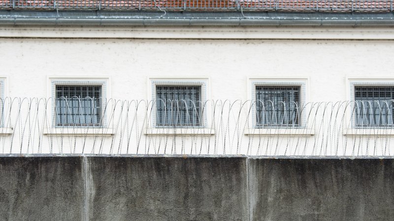 Die JVA Regensburg von außen: Eine hohe Mauer und Stacheldrähte. Dahinter ein Gebäude mit vergitterten Fenstern. | Bild: picture alliance/dpa/Armin Weigel Die JVA Regensburg von außen: Eine hohe Mauer und Stacheldrähte. Dahinter ein Gebäude mit vergitterten Fenstern.