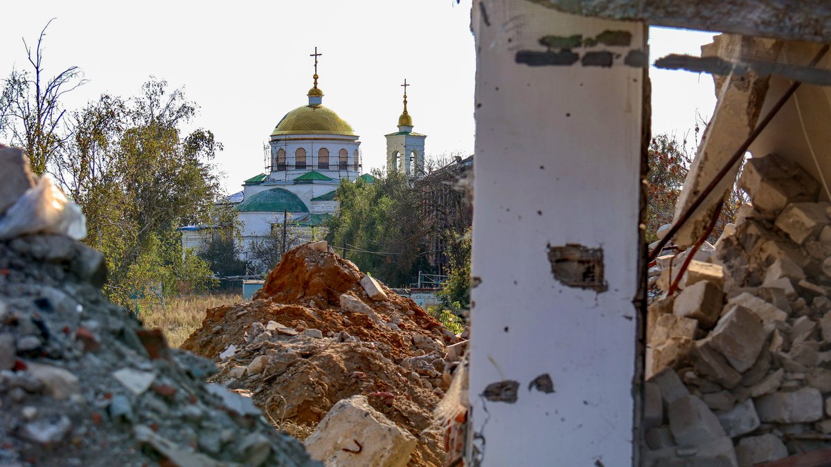 Eine Kirche in der ukrainischen Stadt Isjum hinter einem zerstörten Wohnhaus. 