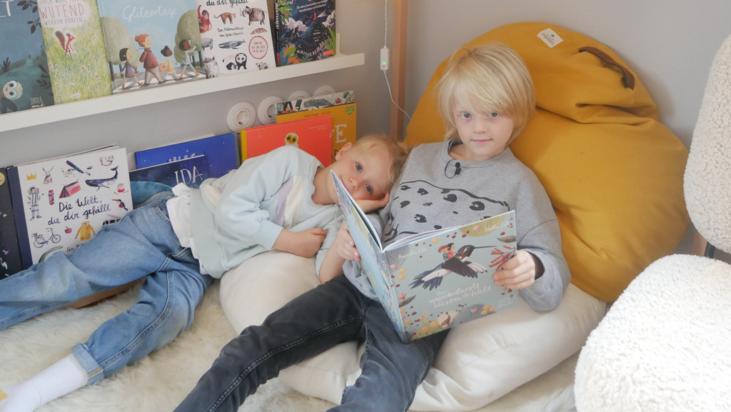 Ein Junge liest seiner Schwester aus einem Buch vor 