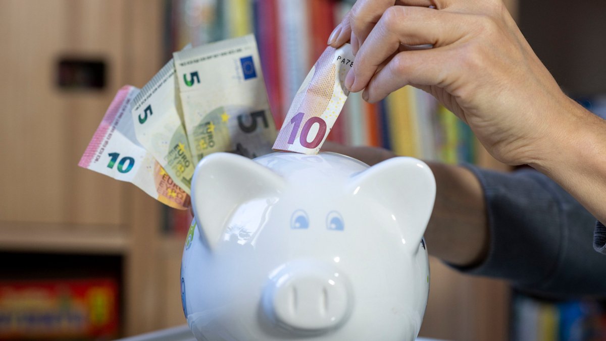 Eine Frau steckt einen 10 Euroschein in ein Sparschwein.