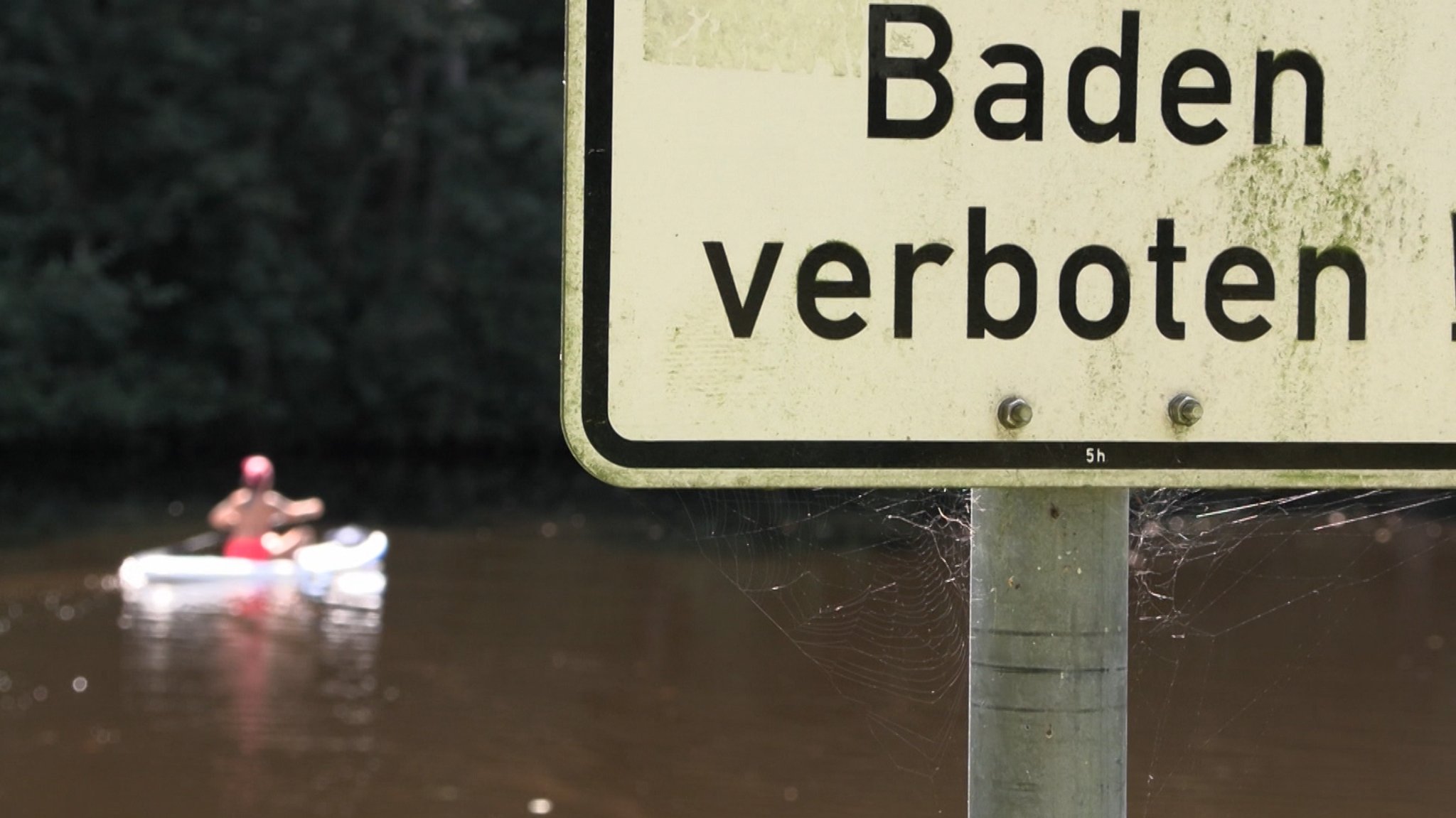 Schild mit "Baden verboten" steht vor einem See