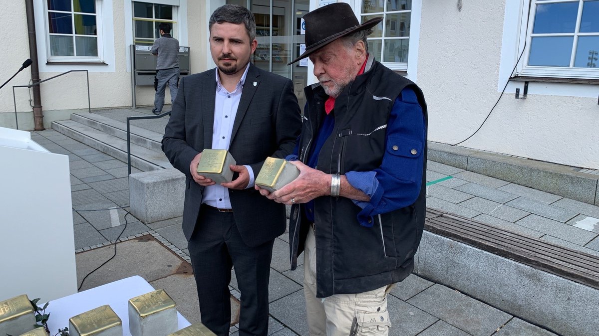 Der Bürgermeister und Gunter Demnig halten Pflastersteine mit den Namen der ermordeten Bürger in der Hand.