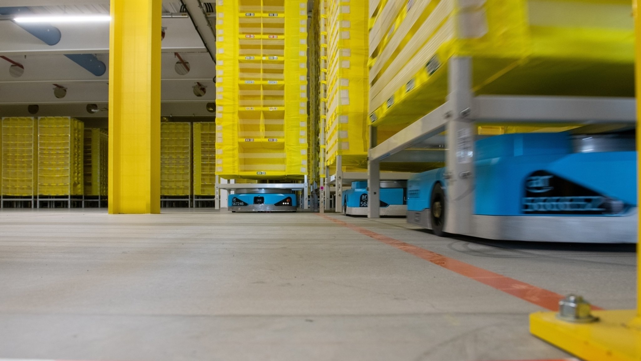 Logistikroboter fahren bei Amazon in Graben im Landkreis Augsburg Paletten durch ein Lager.