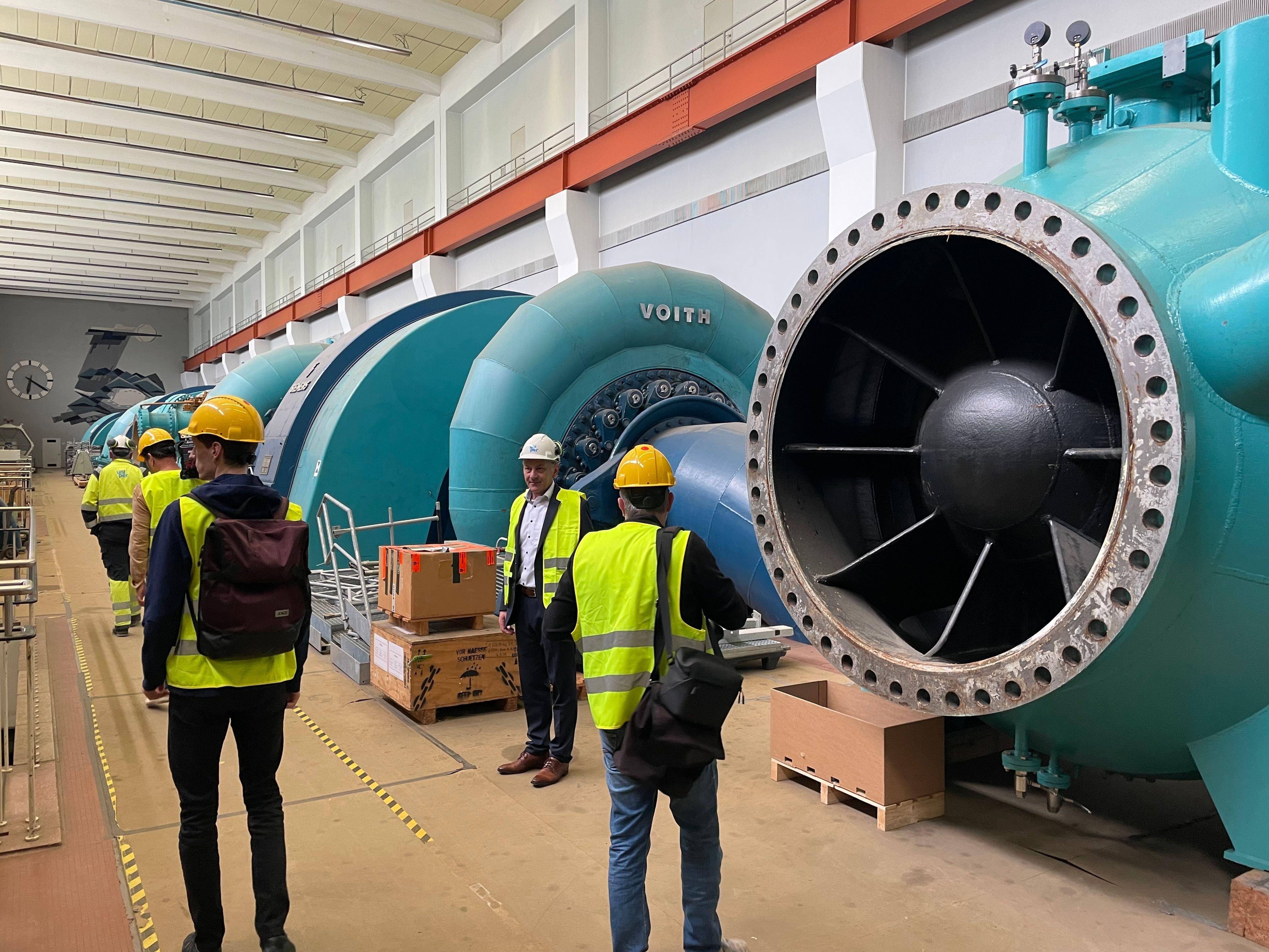 Menschen gehen durch eine Maschinenhalle.