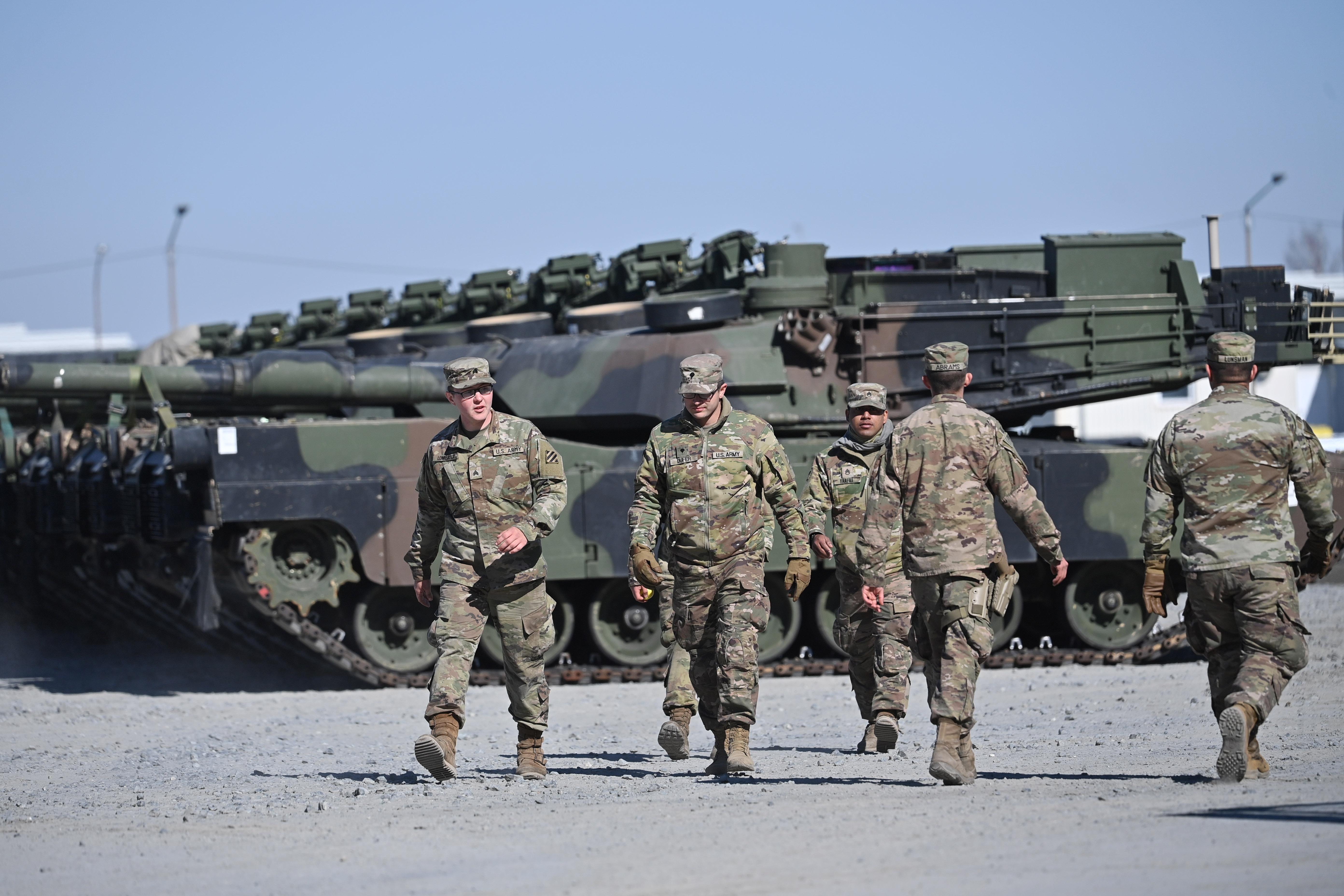 Männer in Tarnkleidung, im Hintergrund Panzer