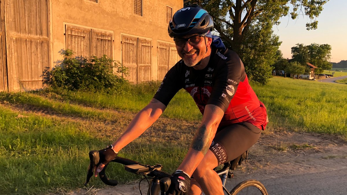 Der 57-Jährige Thomas Metzger fährt lachend auf seinem Rennrad den Berg hinauf.
