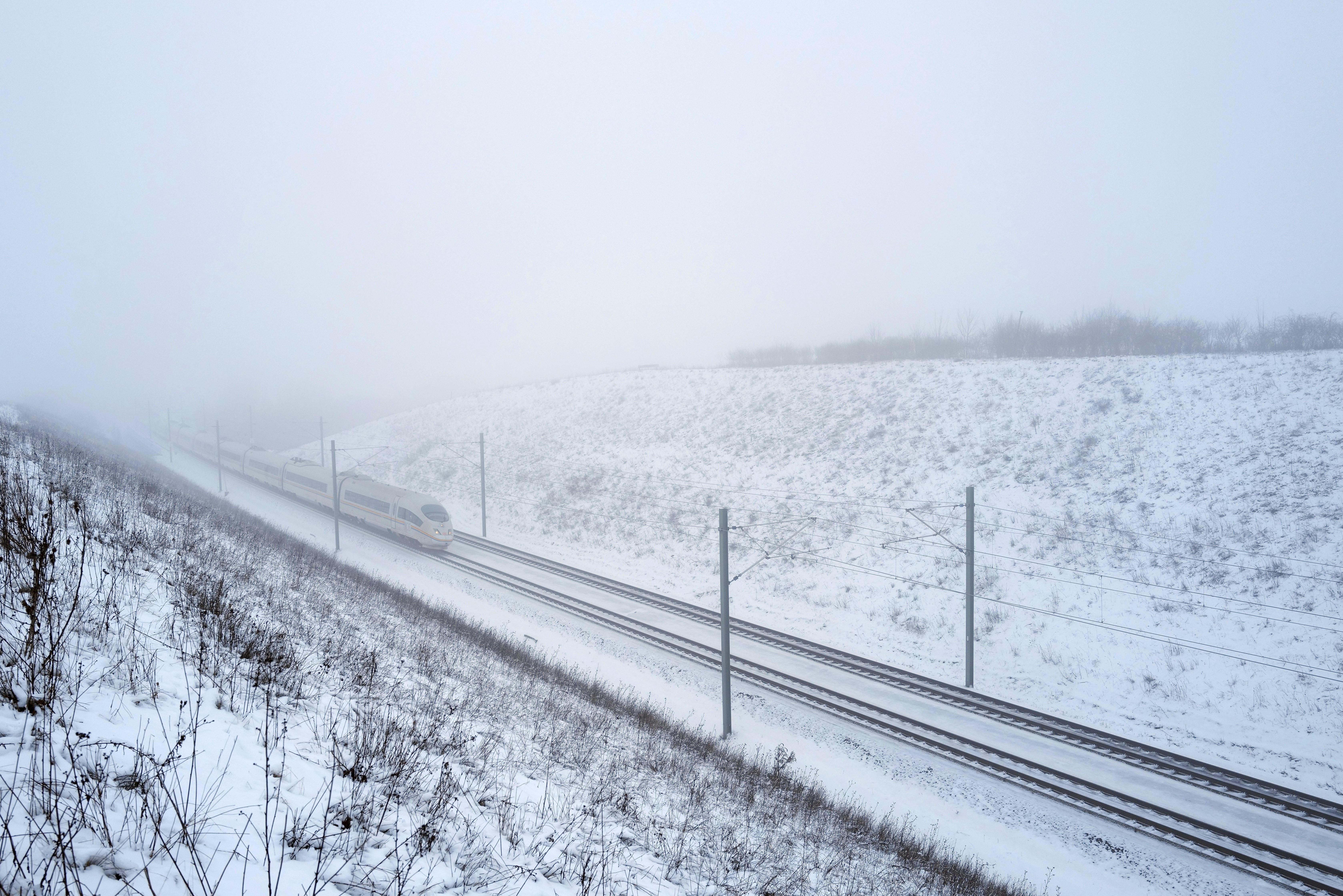 Ein Zug fährt bei Nebel durch eine leicht verschneite Landschaft (Archivbild, 12.01.2026)